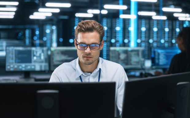 Focused System Administrator or Consultant Look at the Screen and Saves Backup Data in Dark Evening Room Workplace Station Indoors. Network Technologies Concept